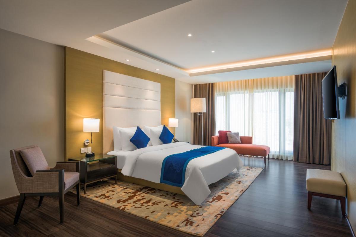 a hotel room with a large bed and a television at Feathers- A Radha Hotel, Chennai in Chennai