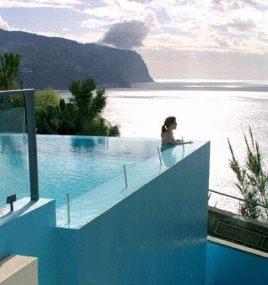 uma mulher sentada na beira de uma piscina em Estalagem Da Ponta Do Sol em Ponta do Sol