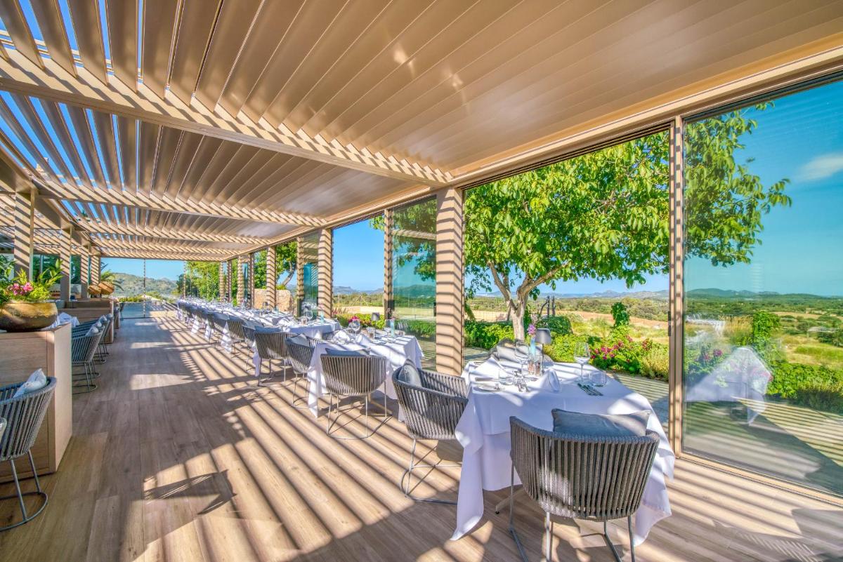 comedor con mesas y sillas en una terraza en Carrossa Hotel & Spa, en Artà