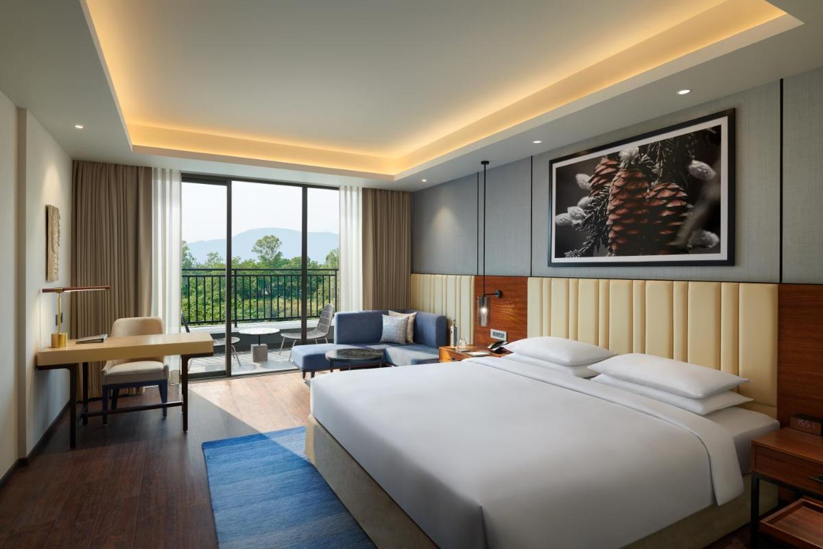 a bedroom with a large white bed and a living room at Hyatt Regency Dehradun Resort and Spa in Dehradun