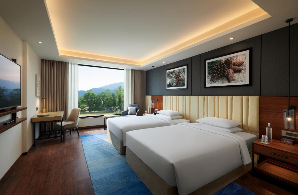 a hotel room with two beds and a desk at Hyatt Regency Dehradun Resort and Spa in Dehradun