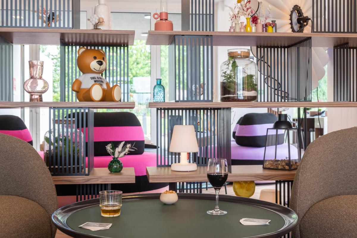 une pièce avec une table et un ours en peluche sur une étagère dans l'établissement Hôtel Omnubo Collection, aux Épesses