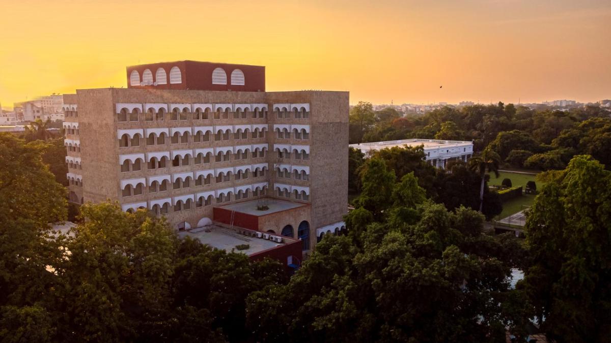 a large building with trees in front of a sunset at Taj Ganges Varanasi in Varanasi