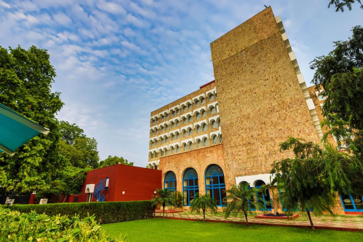 a large brick building with trees in front of it at Taj Ganges Varanasi in Varanasi