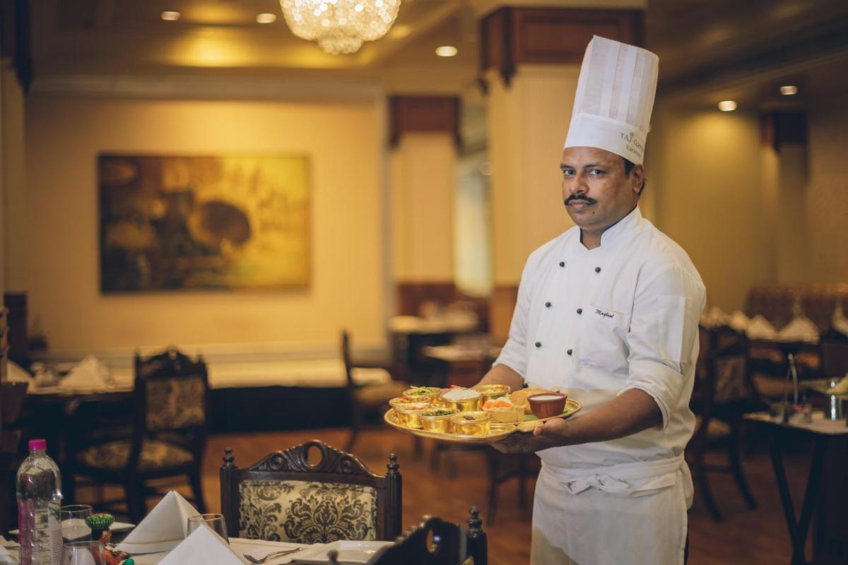 a chef holding a plate of food in a restaurant at Taj Ganges Varanasi in Varanasi