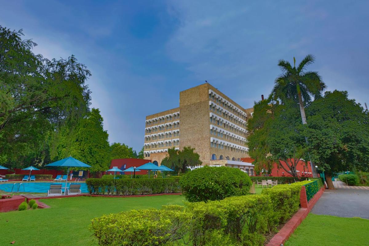 a large building with a palm tree in a park at Taj Ganges Varanasi in Varanasi