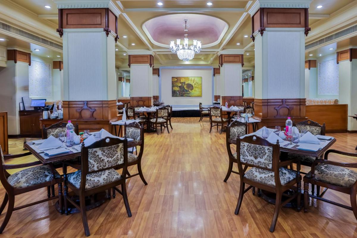 a dining room with tables and chairs and a chandelier at Taj Ganges Varanasi in Varanasi
