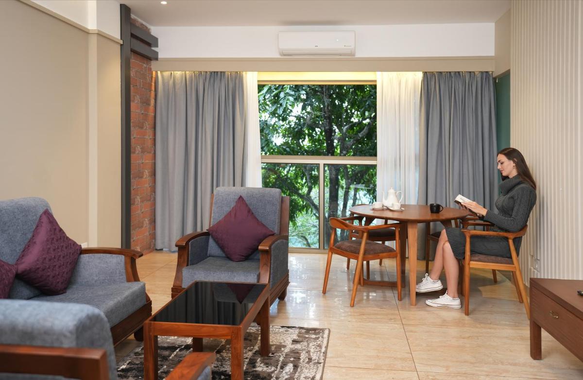 a woman sitting at a table in a living room at Elephant Passage in Munnar