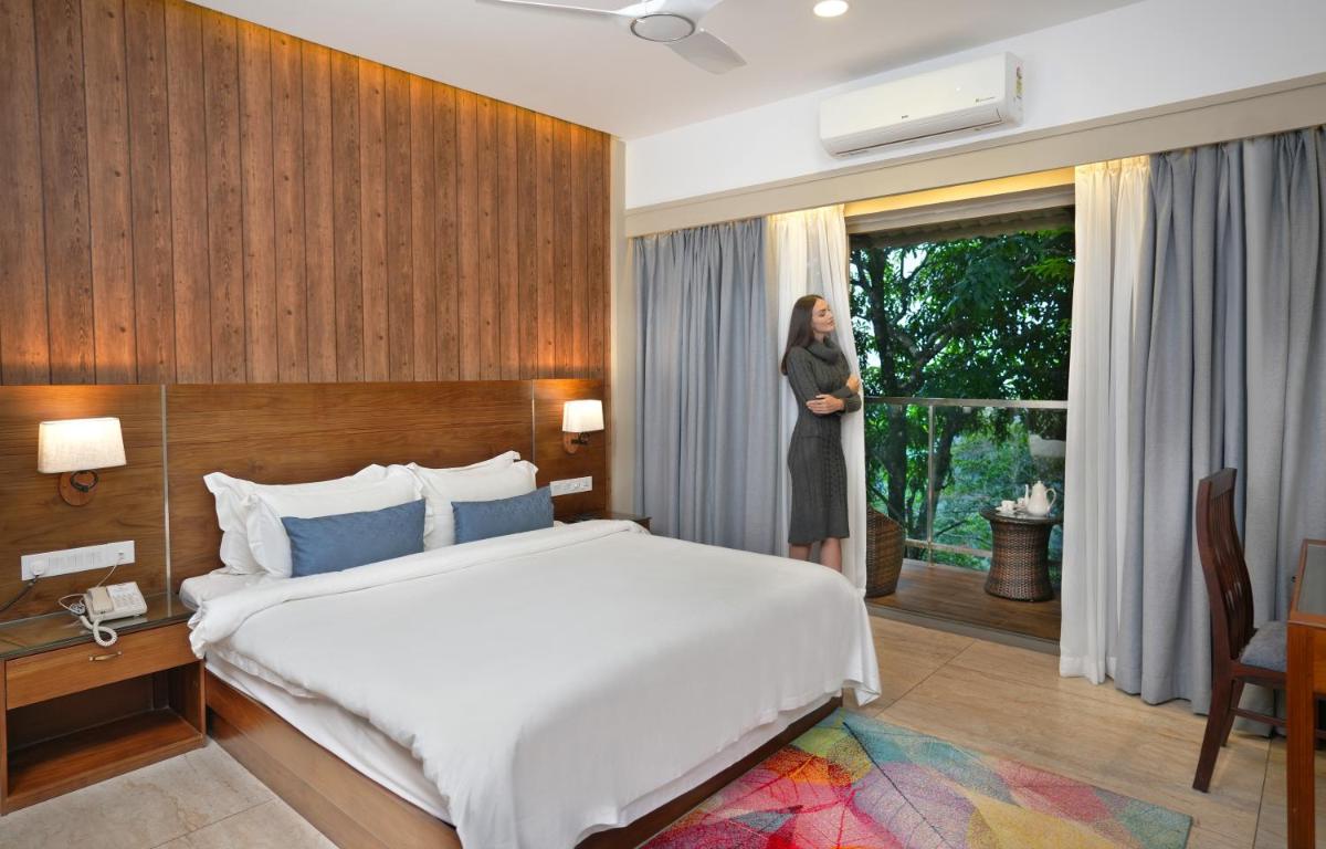 a woman standing in a hotel room with a bed at Elephant Passage in Munnar