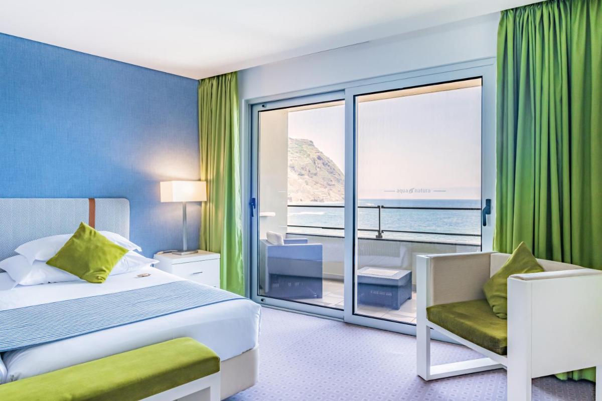 Um quarto com cama e vista para o oceano. em Aqua Natura Madeira em Porto Moniz Um quarto com cama e vista para o oceano. em Aqua Natura Madeira em Porto Moniz