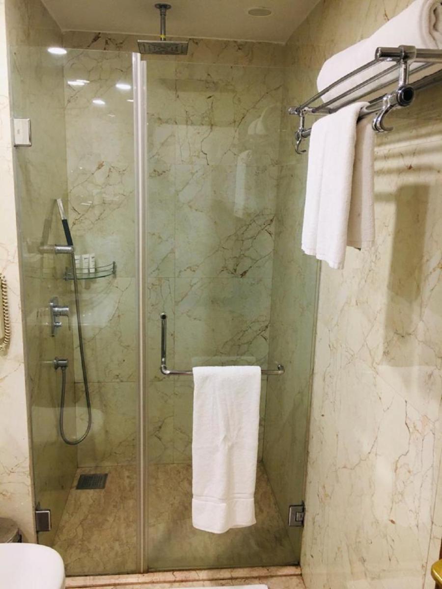 a bathroom with a glass shower stall with towels at Radisson Goa Candolim in Candolim