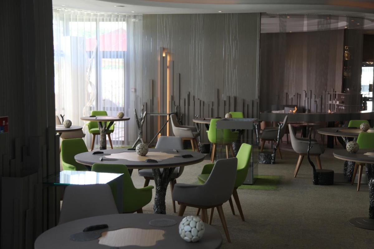 une salle à manger avec des tables et des chaises vertes dans l'établissement Hôtel Le Parc - La Table de Franck Putelat, à Carcassonne