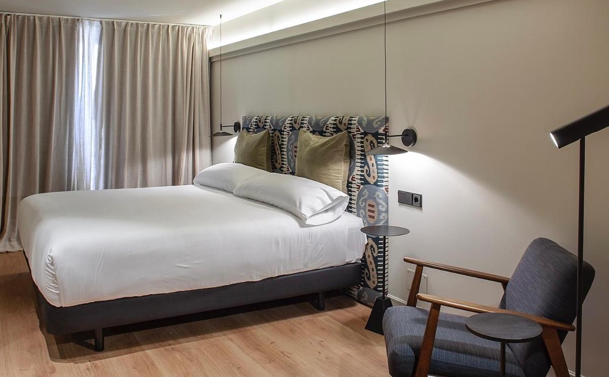 Un dormitorio con una cama blanca y una silla. en Blanco Hotel Spa, en Navia