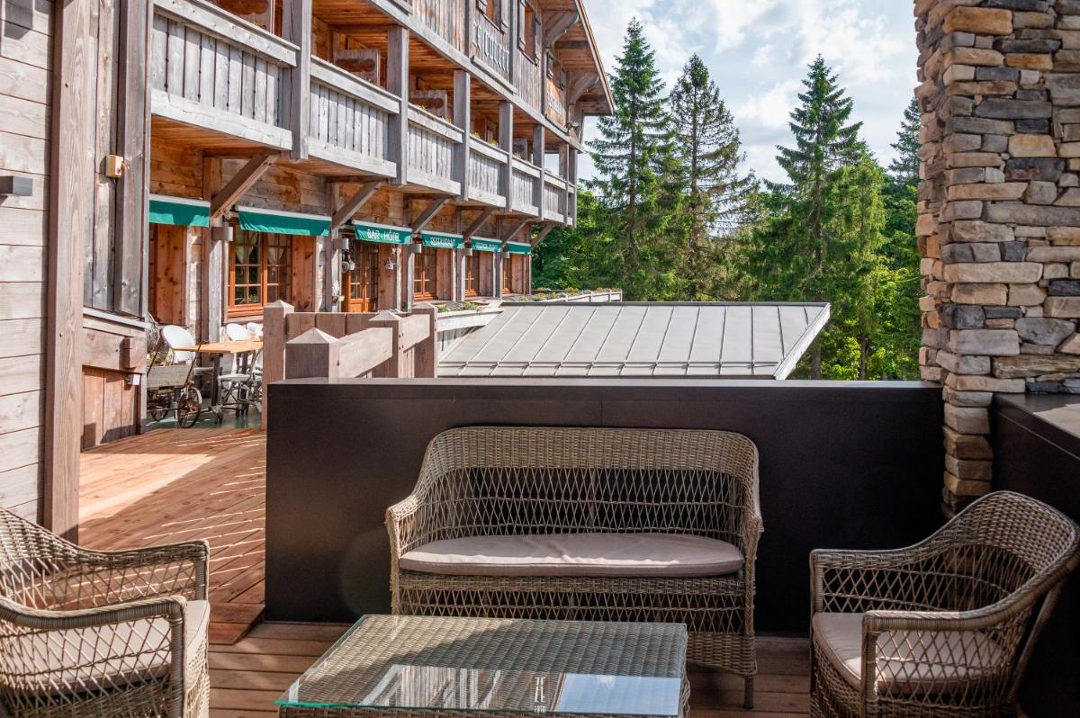 une terrasse avec des chaises en osier et une table dans l'établissement Chalet Hôtel & Spa Le Collet, à Xonrupt-Longemer