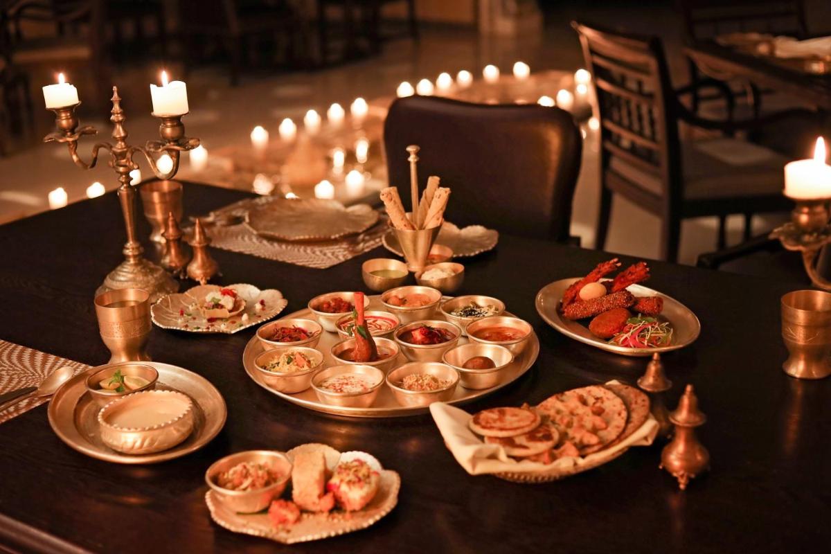 a table with plates of food on a table with candles at The Leela Palace Jaipur in Jaipur
