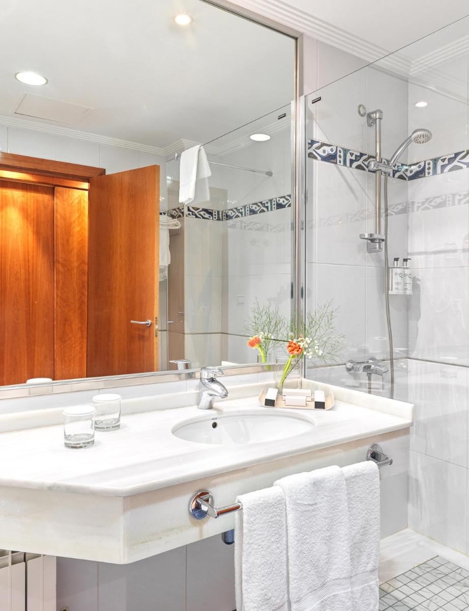 Un baño blanco con lavabo y ducha. en Hotel Spa Galatea, en Sanxenxo