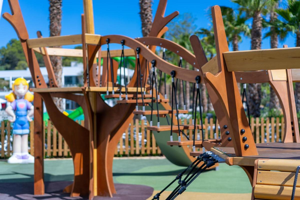 un parque infantil de madera con tobogán en un parque en Alannia Salou, en Salou