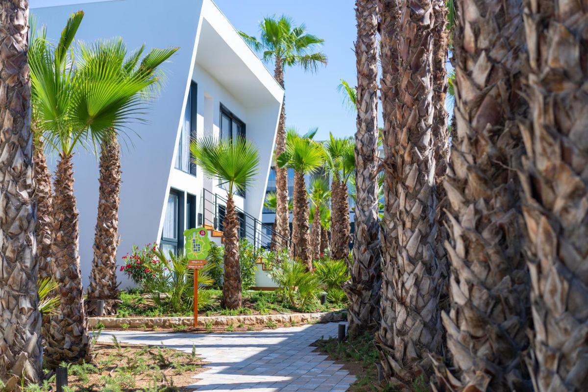 una pasarela a través de palmeras frente a un edificio en Alannia Salou, en Salou