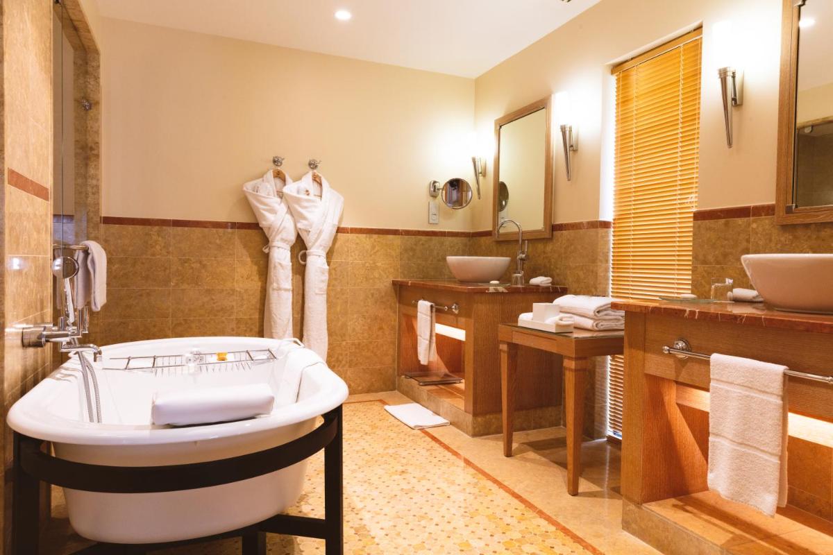une salle de bain avec une baignoire et deux lavabos et une baignoire dans l'établissement Terre Blanche Hotel Spa Golf Resort, à Tourrettes