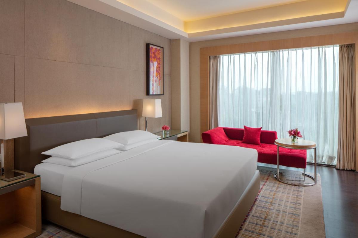 a bedroom with a large white bed and a red chair at Hyatt Regency Chandigarh in Chandīgarh