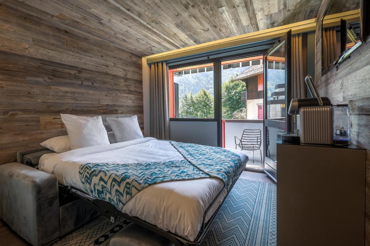 une chambre avec un lit et une grande fenêtre dans l'établissement Chalet Hôtel Le Prieuré & Spa, à Chamonix-Mont-Blanc
