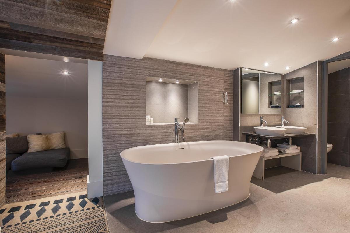 une grande salle de bains avec baignoire et deux lavabos dans l'établissement Chalet Hôtel Le Prieuré & Spa, à Chamonix-Mont-Blanc