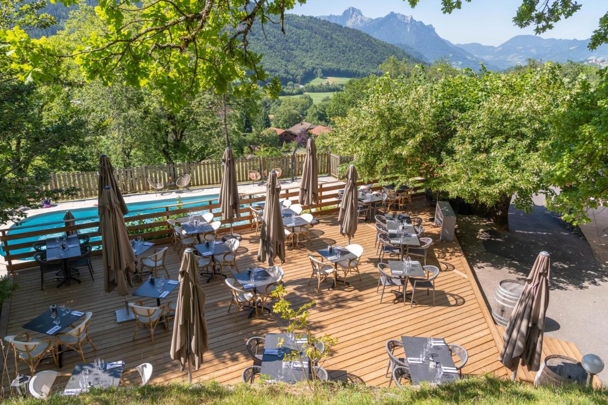 une terrasse en bois avec des tables, des chaises et des parasols dans l'établissement Hotel Le Bois Joli, à Bernex