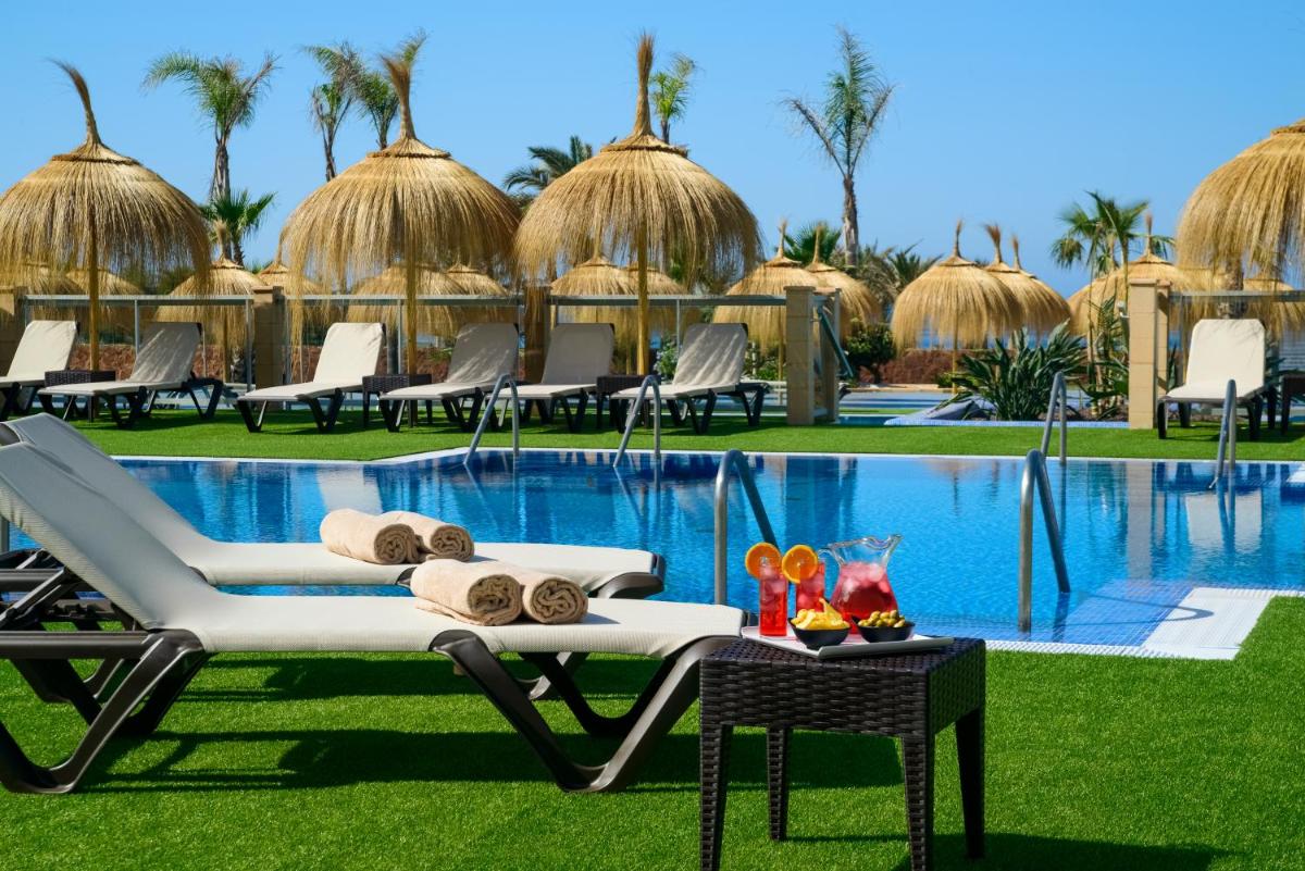 Un complejo con piscina, sillas y mesa. en Cabogata Beach Hotel, en Retamar