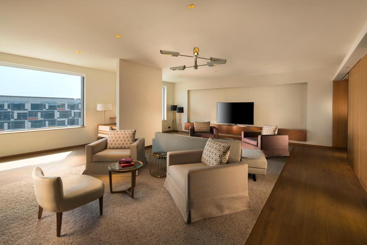 a living room with couches and a large window at Andaz Delhi, by Hyatt in New Delhi a living room with couches and a large window at Andaz Delhi, by Hyatt in New Delhi