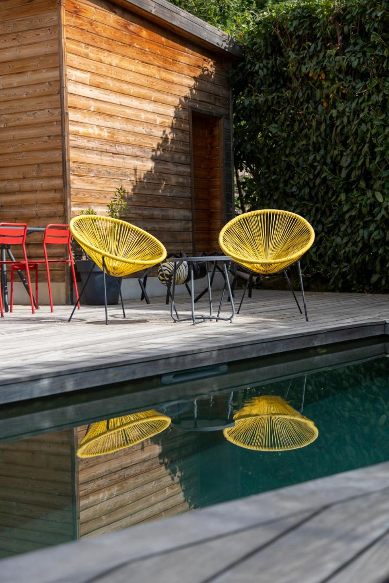 3 tables et chaises jaunes à côté d'une piscine dans l'établissement Artemisia Boutique Hotel, à Bastelica