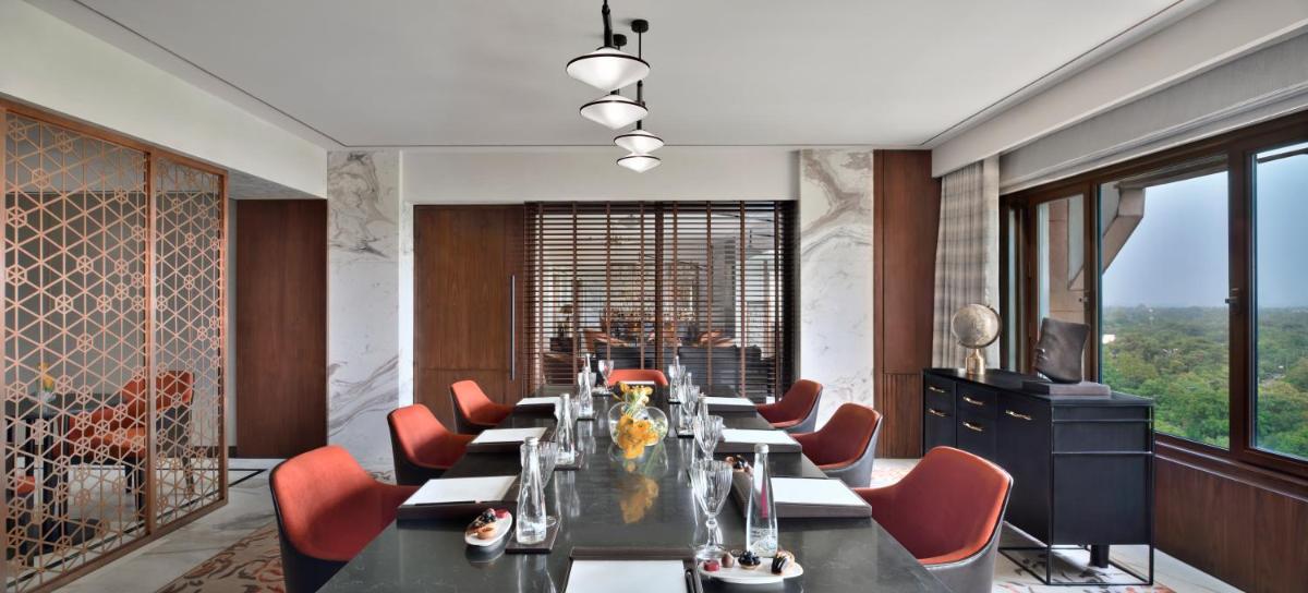 a dining room with a long table and red chairs at Taj Mahal, New Delhi in New Delhi