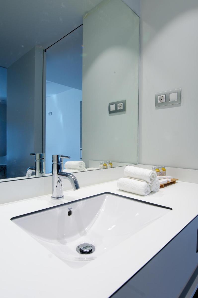 lavabo blanco con espejo grande en Hotel Terra Bonansa, en Bonansa