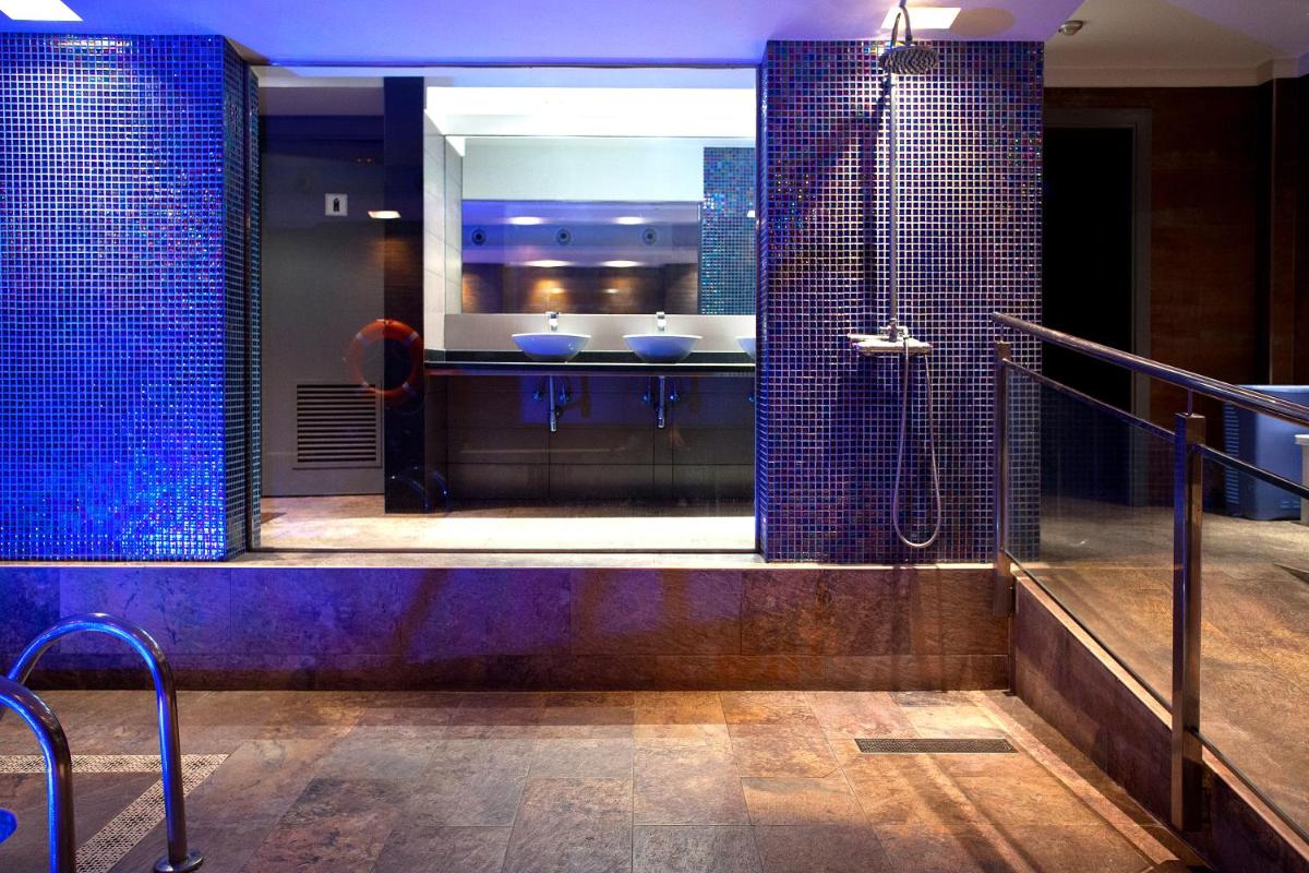 baño con 2 lavabos y ducha con azulejos azules en Hotel Acacias Suites & Spa, en Lloret de Mar