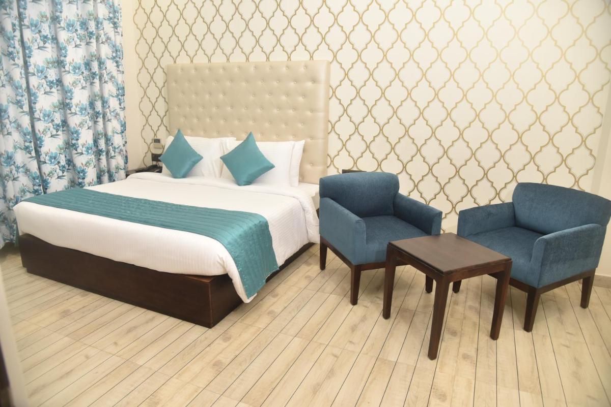 a bedroom with a bed and two blue chairs at The Orchid Shimla in Shimla