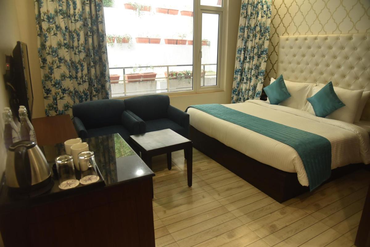 a hotel room with a bed and a couch and a window at The Orchid Shimla in Shimla