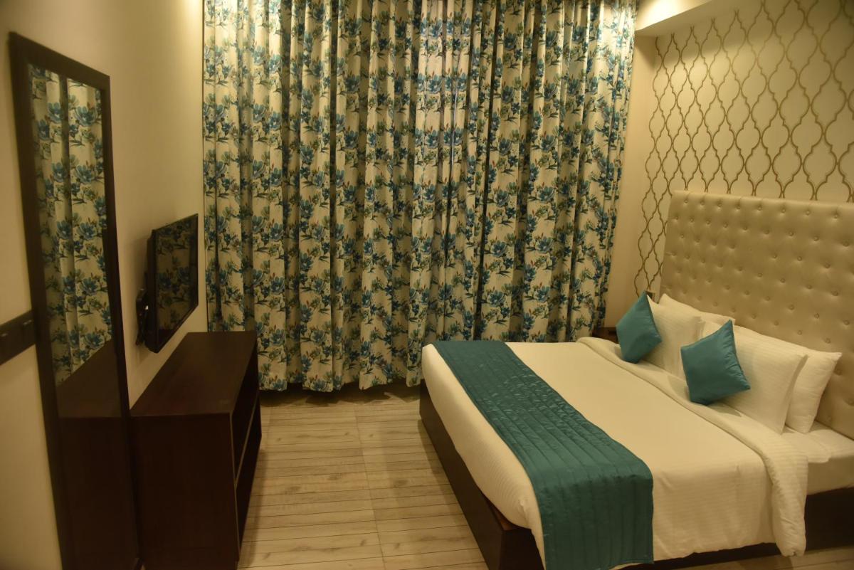 a bedroom with a bed and a mirror and curtains at The Orchid Shimla in Shimla