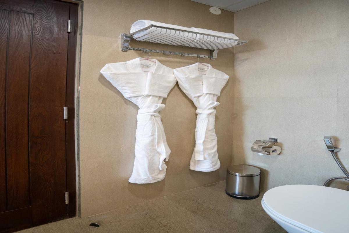 two white pants hanging on a wall in a bathroom at The Orchid Shimla in Shimla
