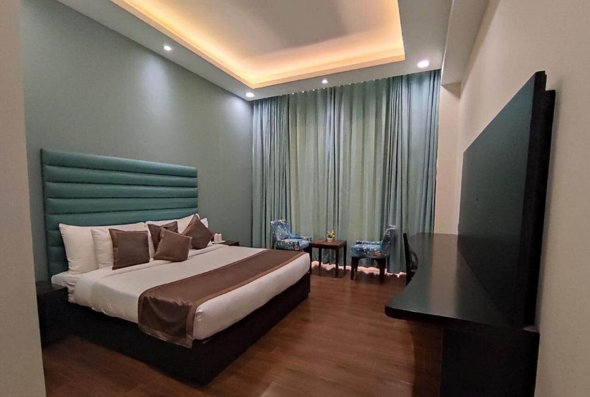 a bedroom with a large bed with a green headboard at The Orchid Shimla in Shimla