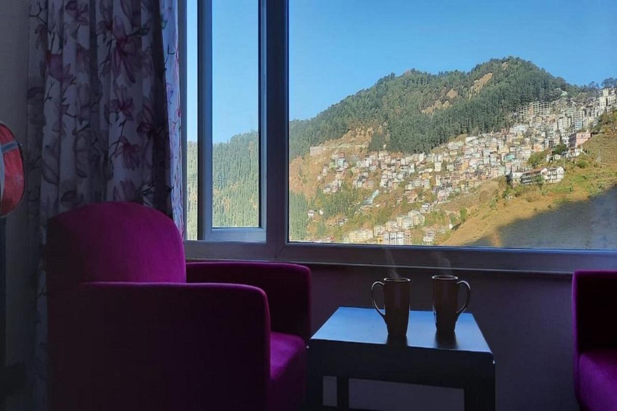 a living room with a view of a mountain from a window at The Orchid Shimla in Shimla