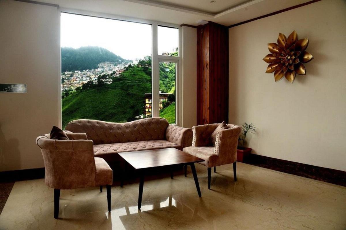 a living room with a couch and chairs and a large window at The Orchid Shimla in Shimla