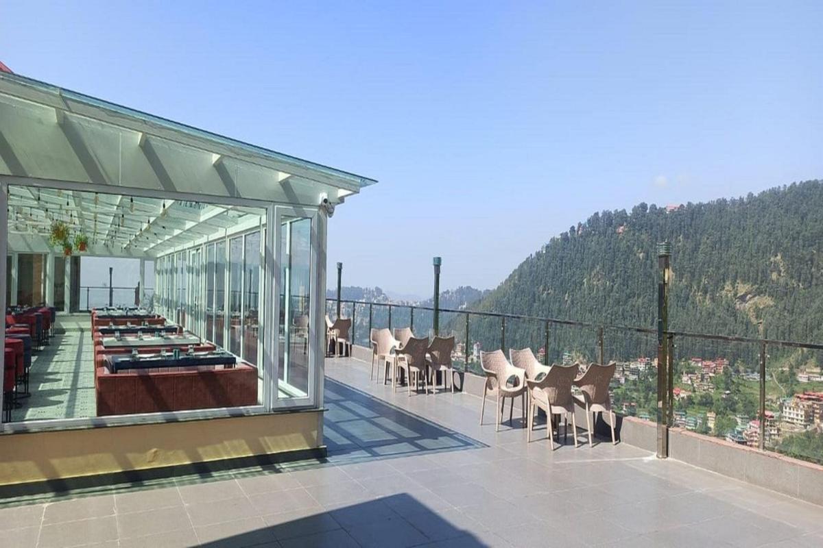 a balcony with a table and chairs on a building at The Orchid Shimla in Shimla