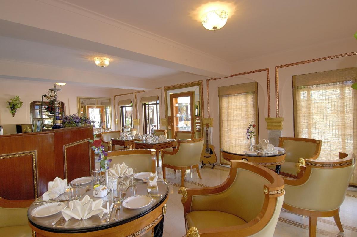 a dining room with tables and chairs and windows at The Raj Palace (Small Luxury Hotels of the World) in Jaipur