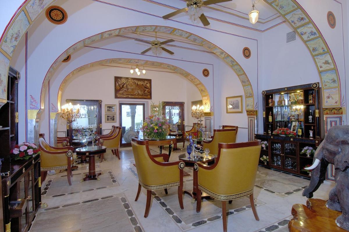 a living room with yellow chairs and a table at The Raj Palace (Small Luxury Hotels of the World) in Jaipur