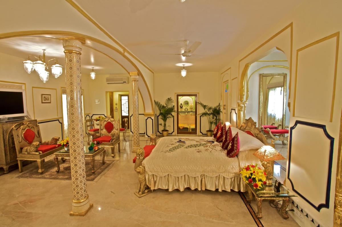a bedroom with a bed and a living room at The Raj Palace (Small Luxury Hotels of the World) in Jaipur
