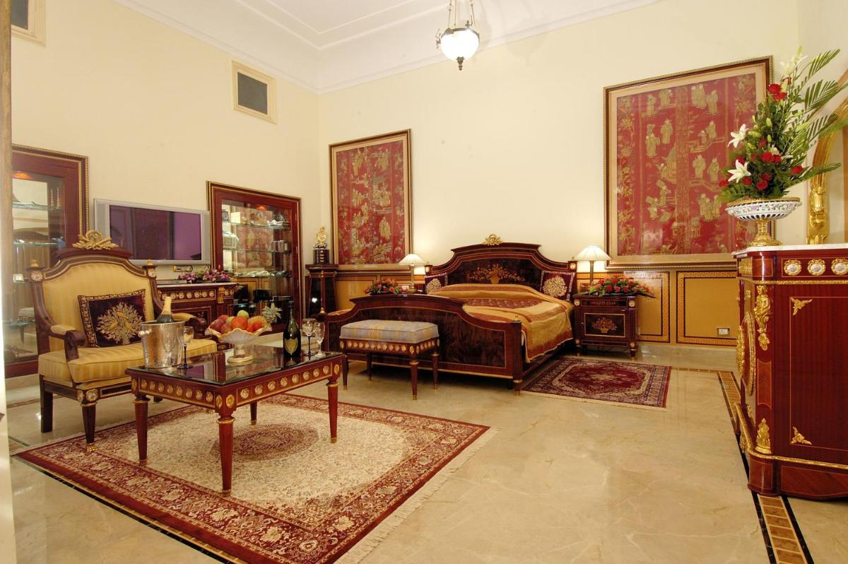 a bedroom with a bed and a table and chairs at The Raj Palace (Small Luxury Hotels of the World) in Jaipur