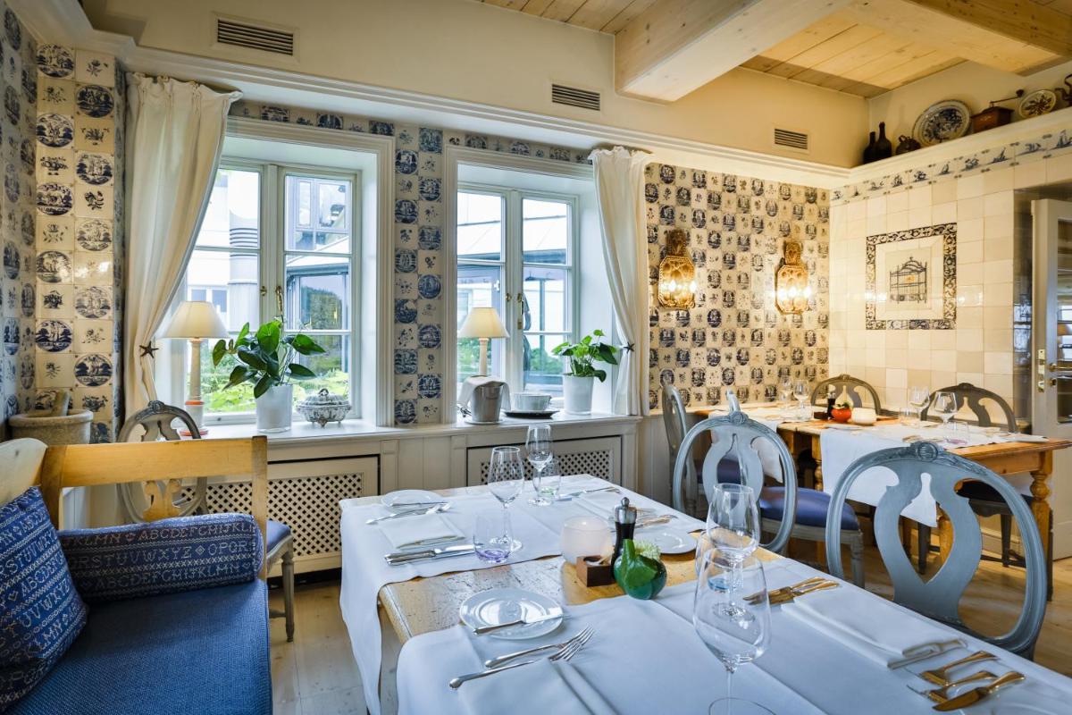 ein Restaurant mit weißen Tischen und Stühlen und Fenstern in der Unterkunft Hotel Fährhaus in Munkmarsch