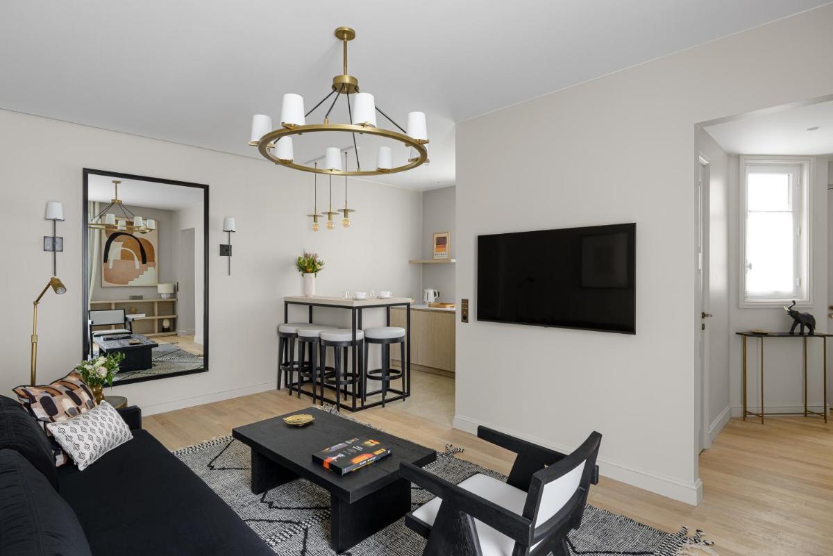 un salon avec un canapé et une télévision sur un mur dans l'établissement Black Door, à Paris