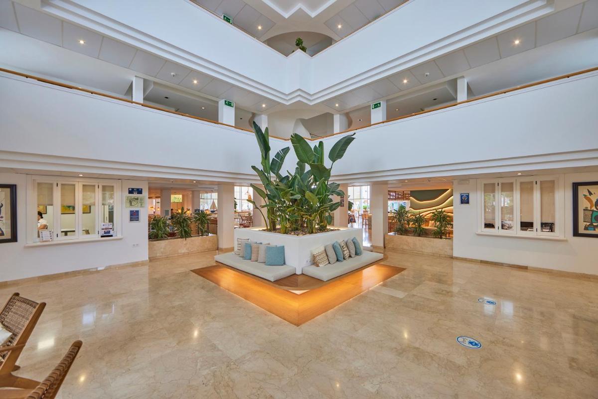 un gran vestíbulo con una gran planta en el medio en Aparthotel Ponent Mar, en Palmanova 116 fotos más