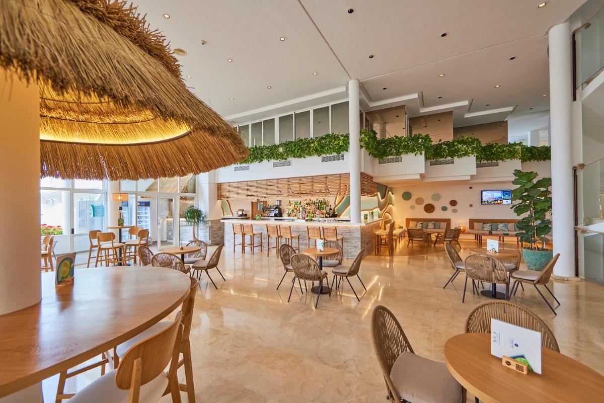 Un restaurante con mesas y sillas y un bar. en Aparthotel Ponent Mar, en Palmanova