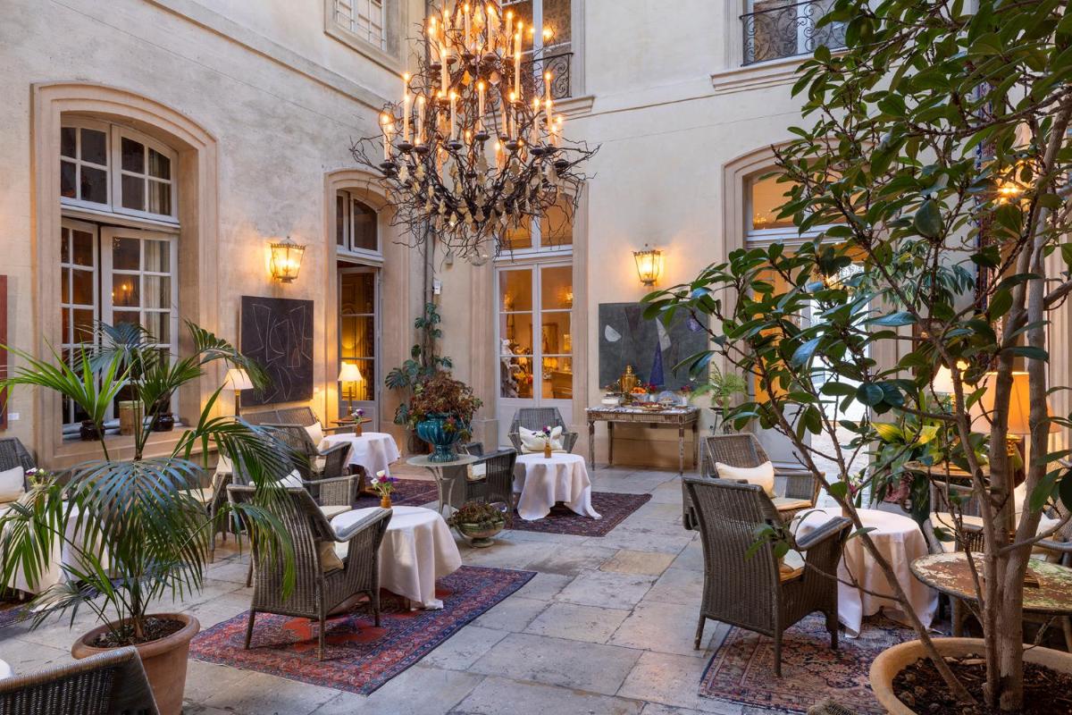 un restaurant avec des tables, des chaises et un lustre dans l'établissement La Mirande, à Avignon